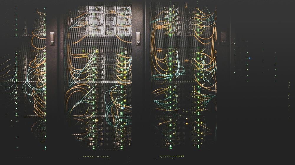 Server cabinets with amber and teal cabling in a dark room